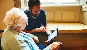 Aide assisting senior use computer